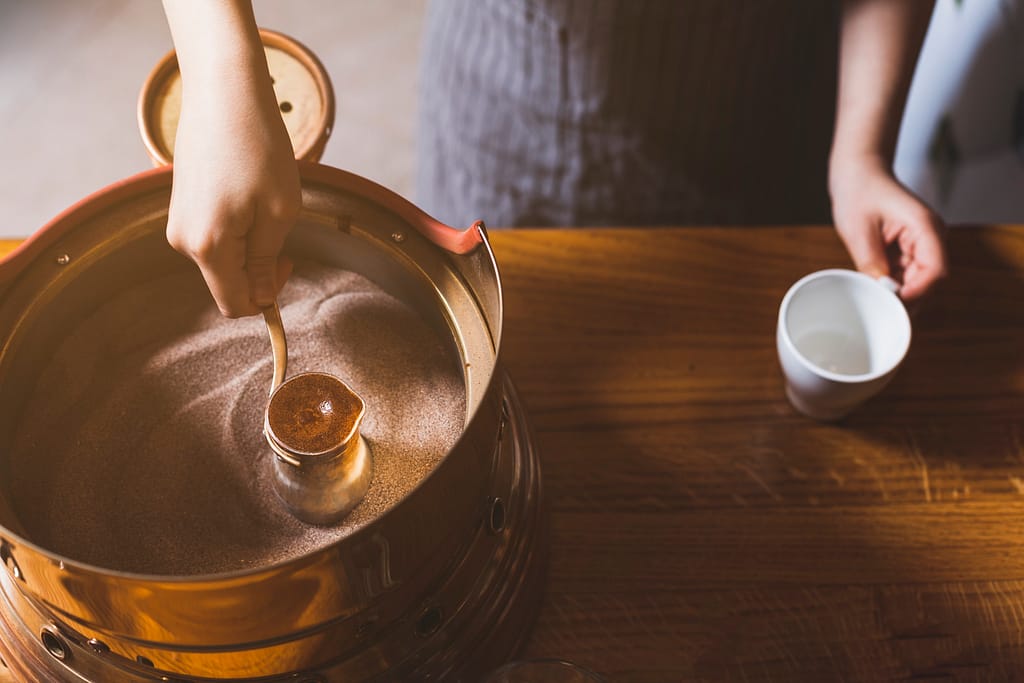 top-view-female-hand-preparing-turkish-coffee-sand.jpg