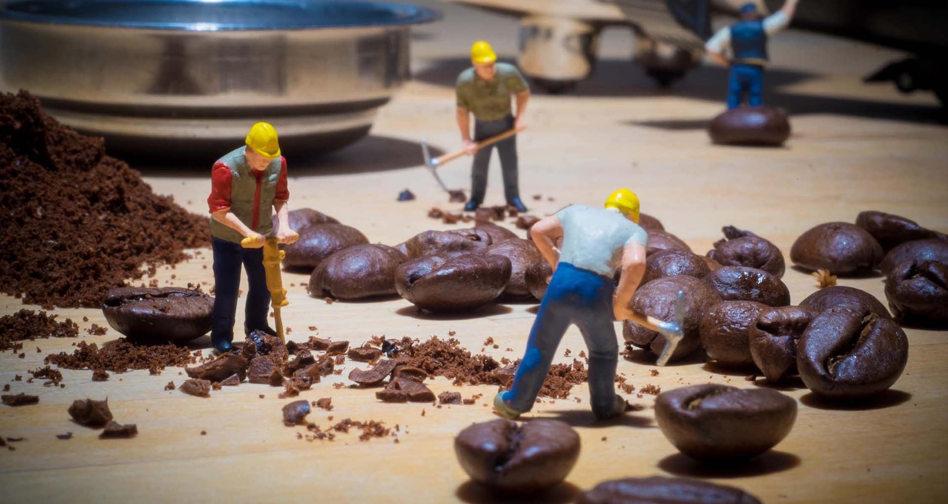 A group of miniature people working on coffee beans
Description automatically generated